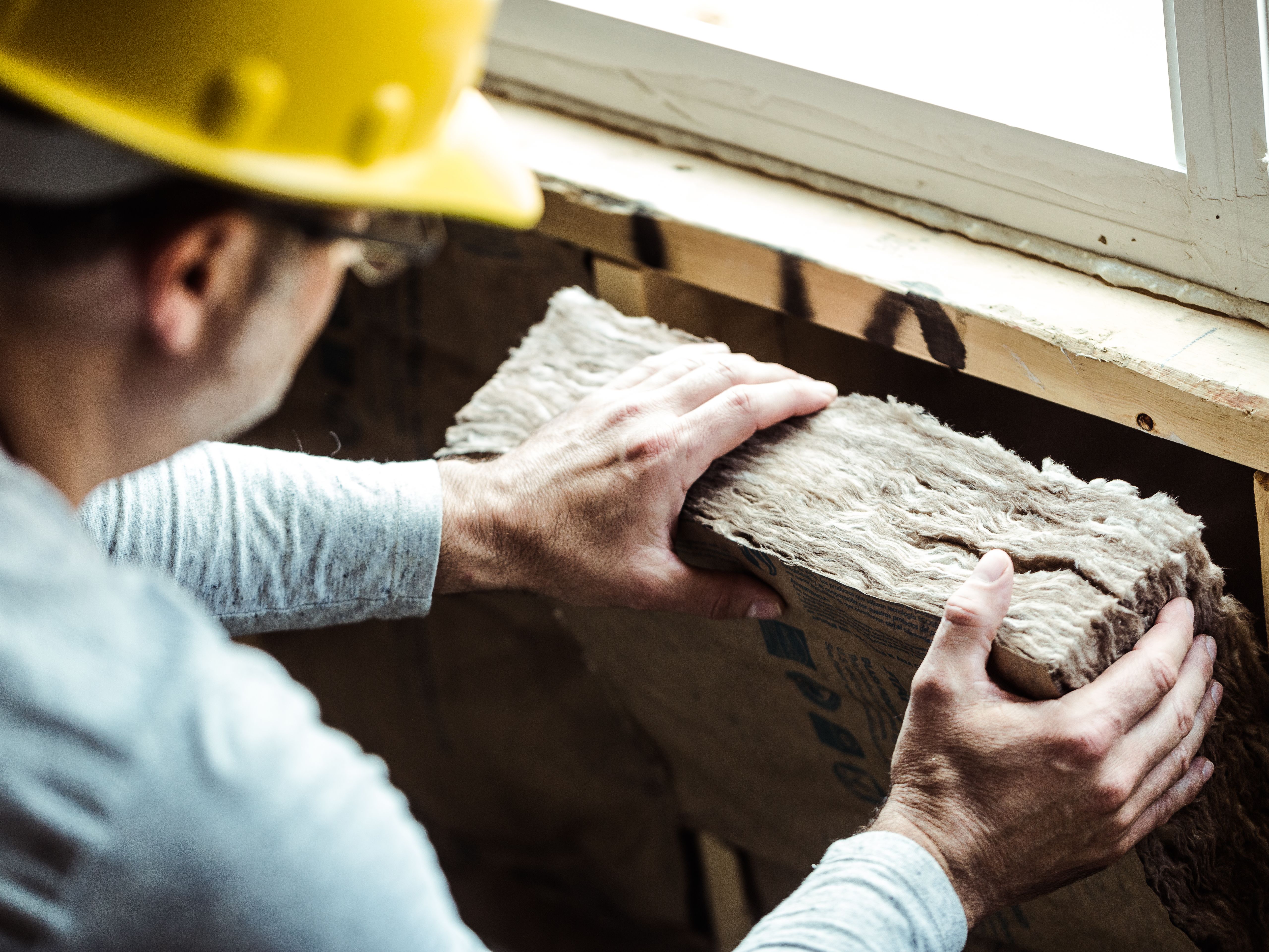 Man installing fiberglass batt insulation